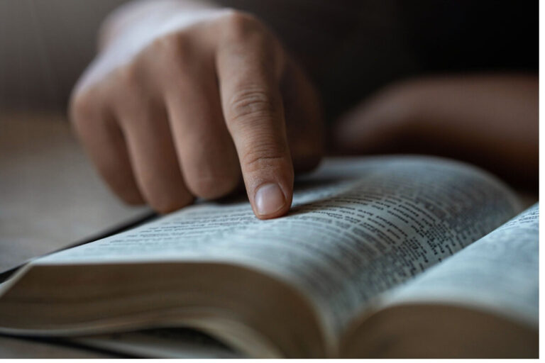 Mão apontando para a Bíblia aberta representando versículos sobre o Espírito Santo no Antigo Testamento