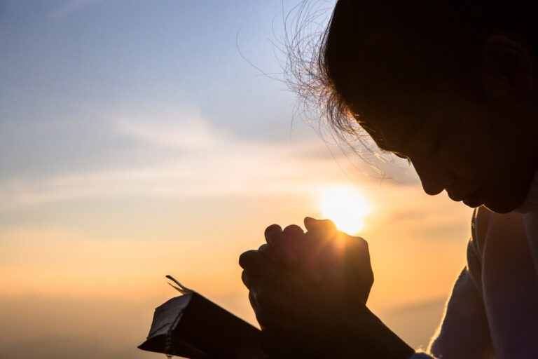 Pessoa orando ao pôr do sol com a Bíblia aberta representando exemplos de jejum na Bíblia e seus propósitos